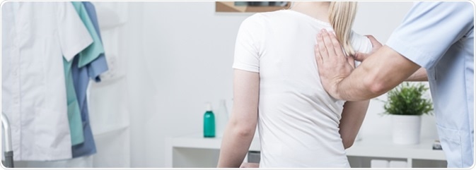 Physiotherapist is rehabilitating patient with spine deformation. Image Credit: Photographee.eu / Shutterstock