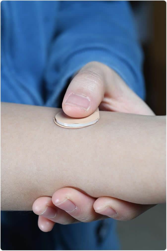 An experimental microneedle patch is shown next to a blister pack of birth control pills. Designed to be self-administered by women for long-acting contraception, the patch could provide a new family planning option. (Credit: Christopher Moore, Georgia Tech)
