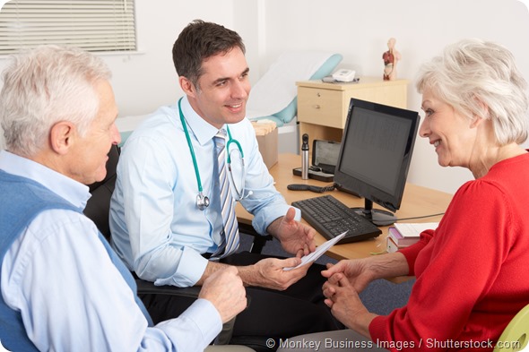 British GP talking to senior couple in surgery