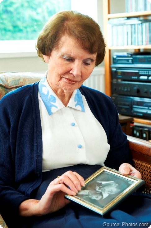 Senior Woman looking sadly at old wedding photograph Senior Woman looking sadly at old wedding photograph