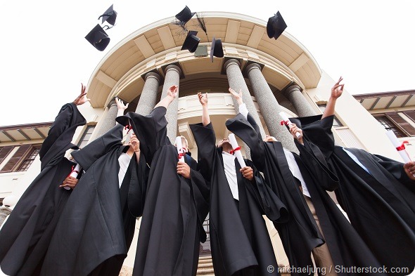 group of happy graduates throwing graduation hats in the air celebrating