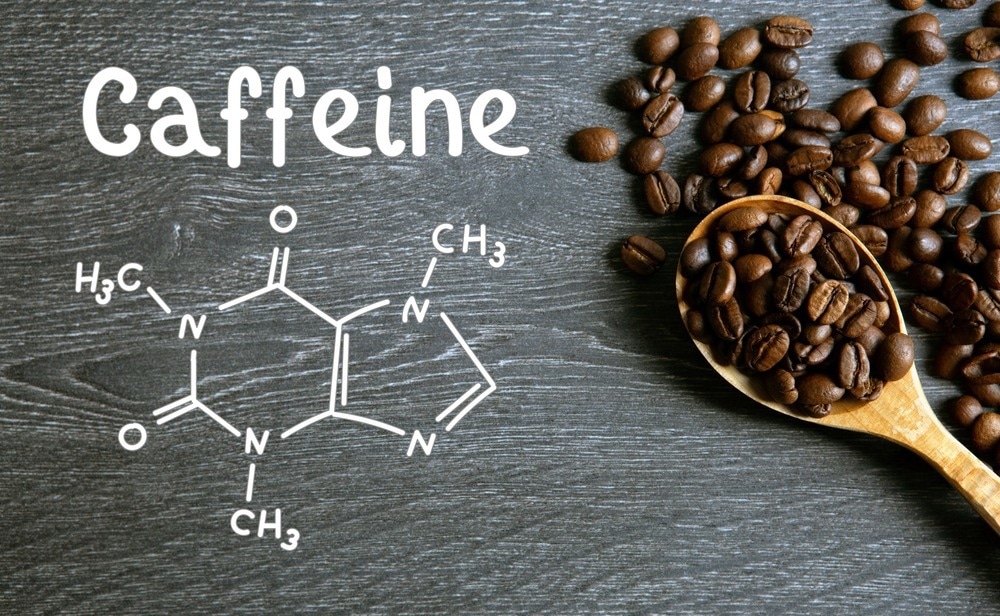 Coffee beans with wooden spoon and chemical structure of caffeine on a wooden table