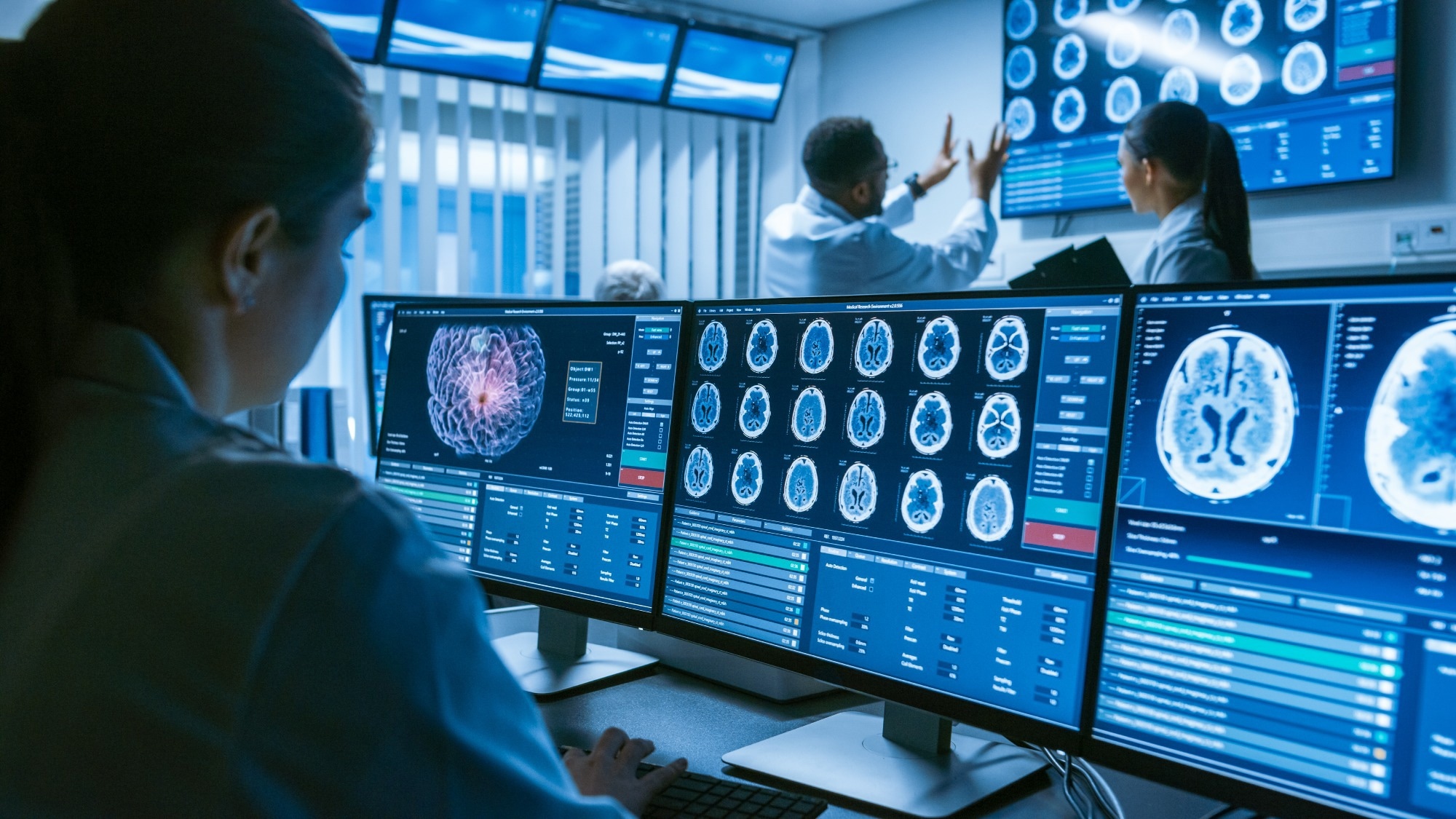 Over the Shoulder Shot of Female Medical Scientist Working with Brain Scan Images on a Personal Computer in Laboratory.