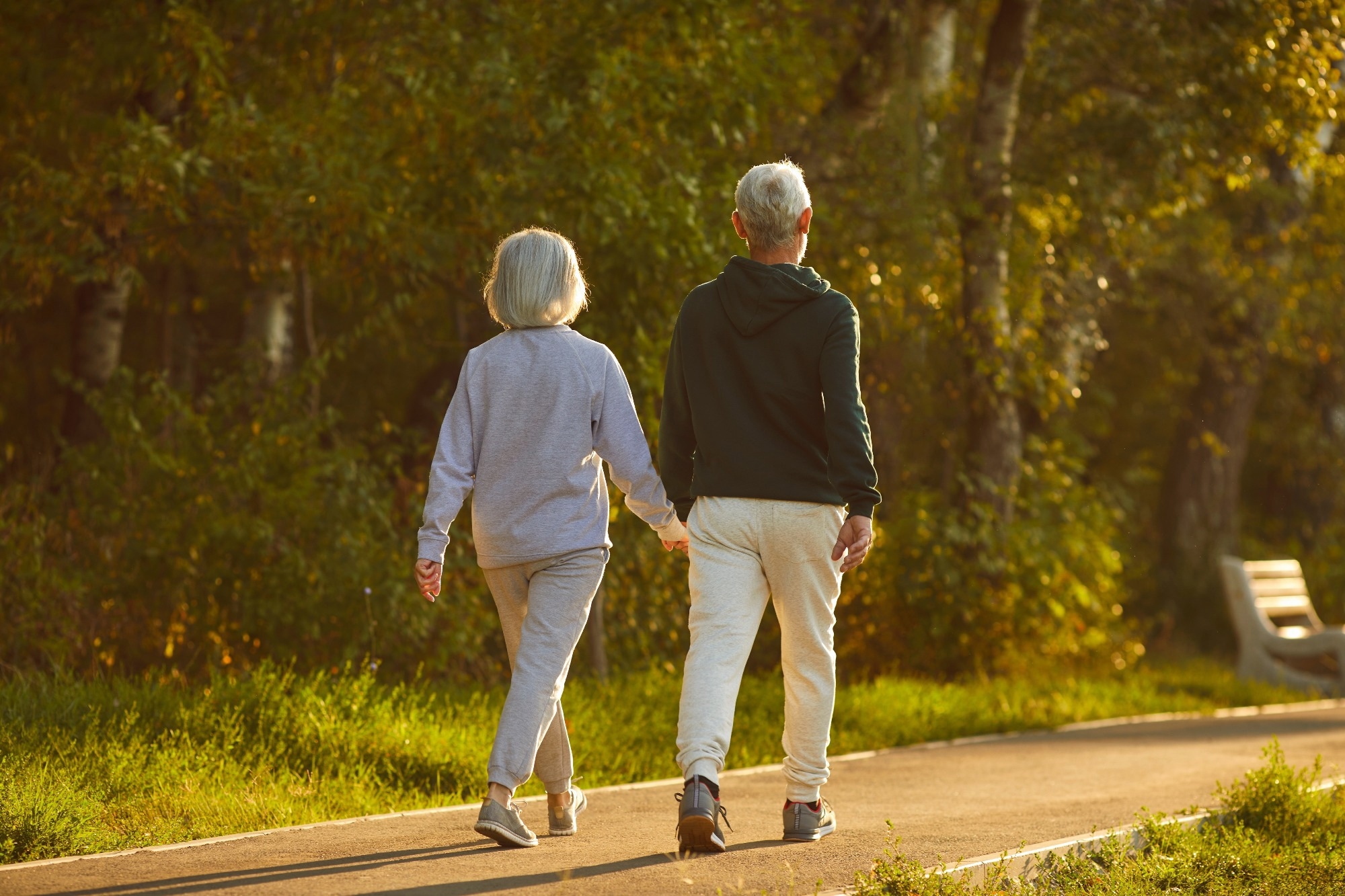 Married senior couple walking together on a sunny summer evening.