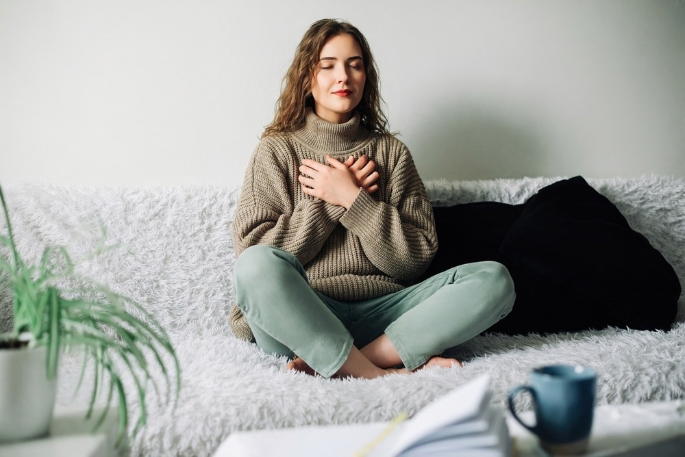 Woman practicing pranayama in lotus position on bed