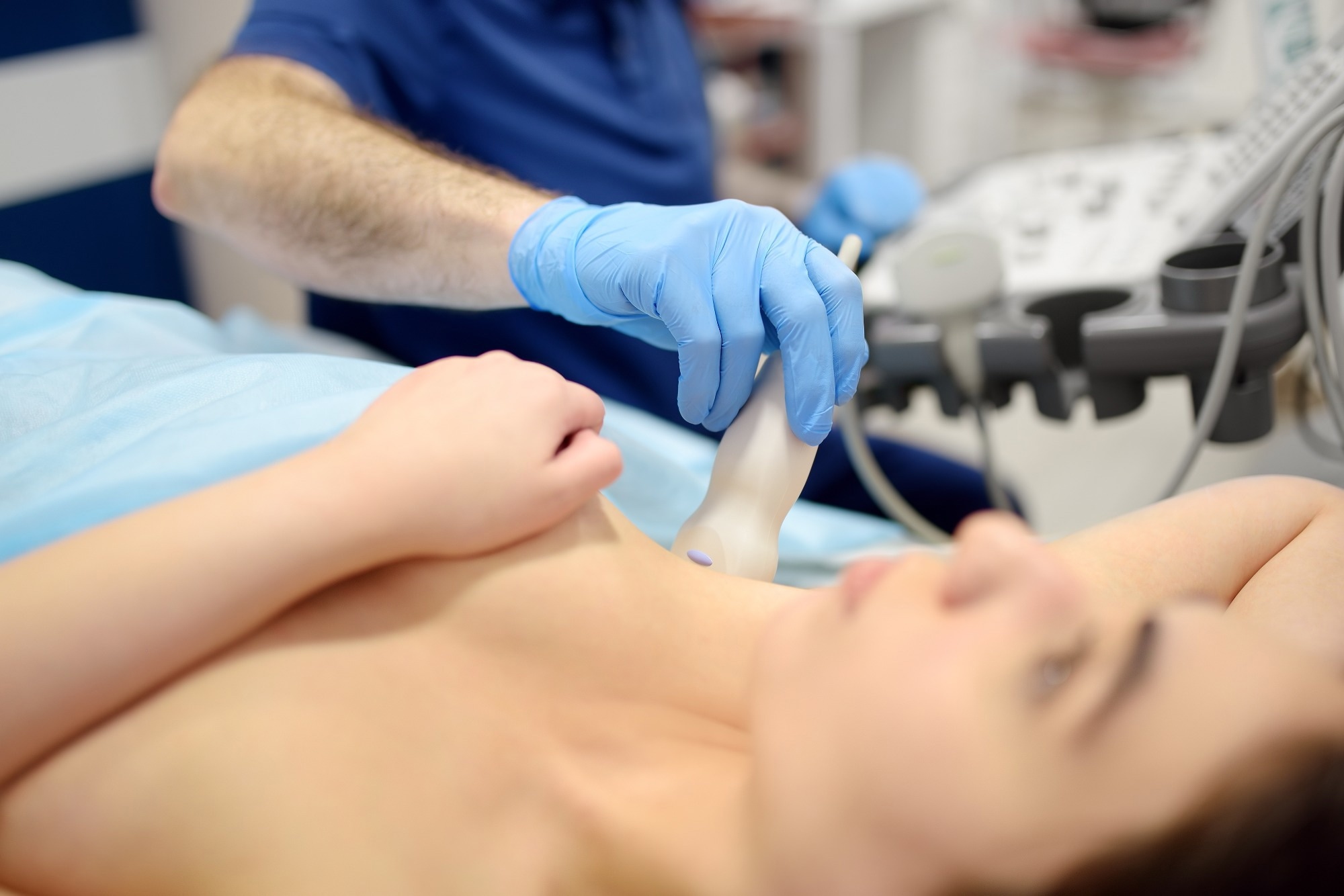 Mammologist doctor examines a woman breasts and lymph nodes using ultrasound