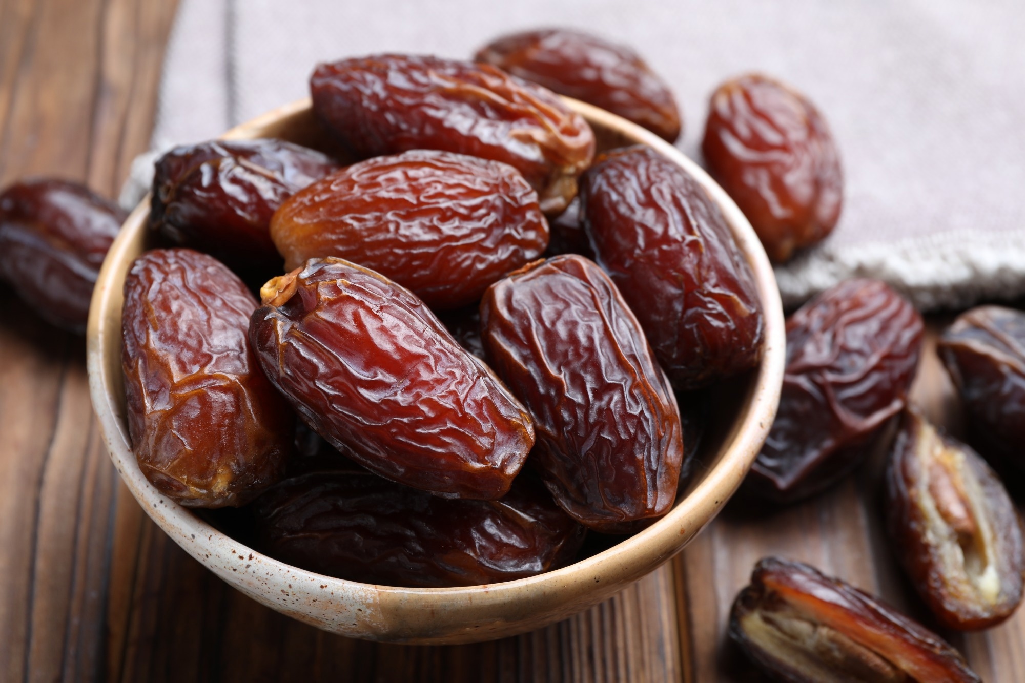 Many tasty dried dates in bowl on wooden table, closeup