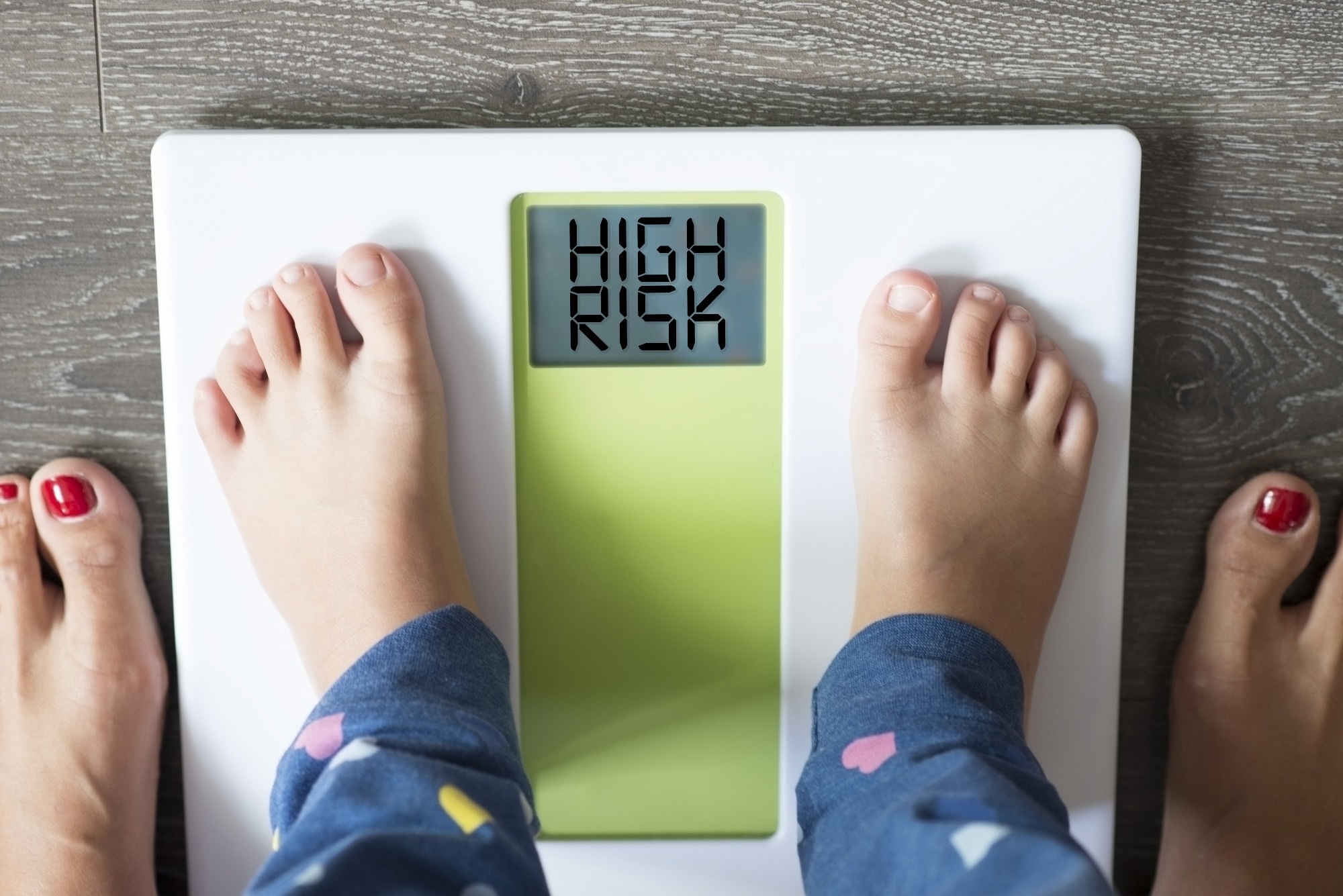 child’s feet on weight scale under the supervision of his mother