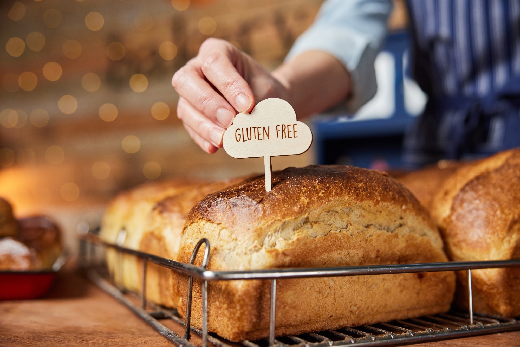 Sales Assistant In Bakery Putting Gluten Free Label Into Freshly Baked Bread