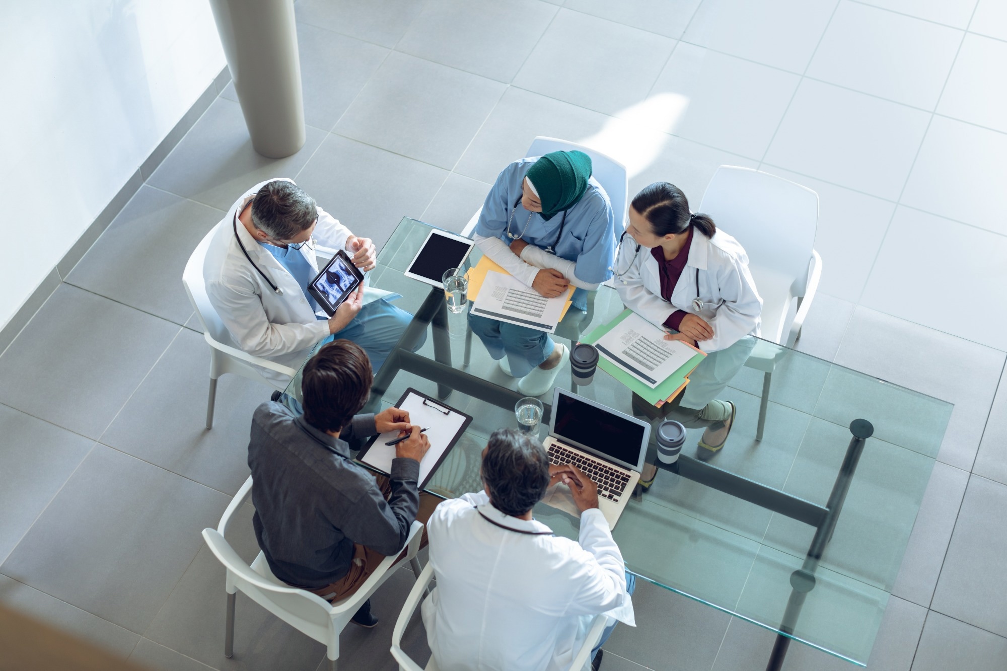 High angle view of diverse medical team discussing x-ray report over digital tablet at table in hospital