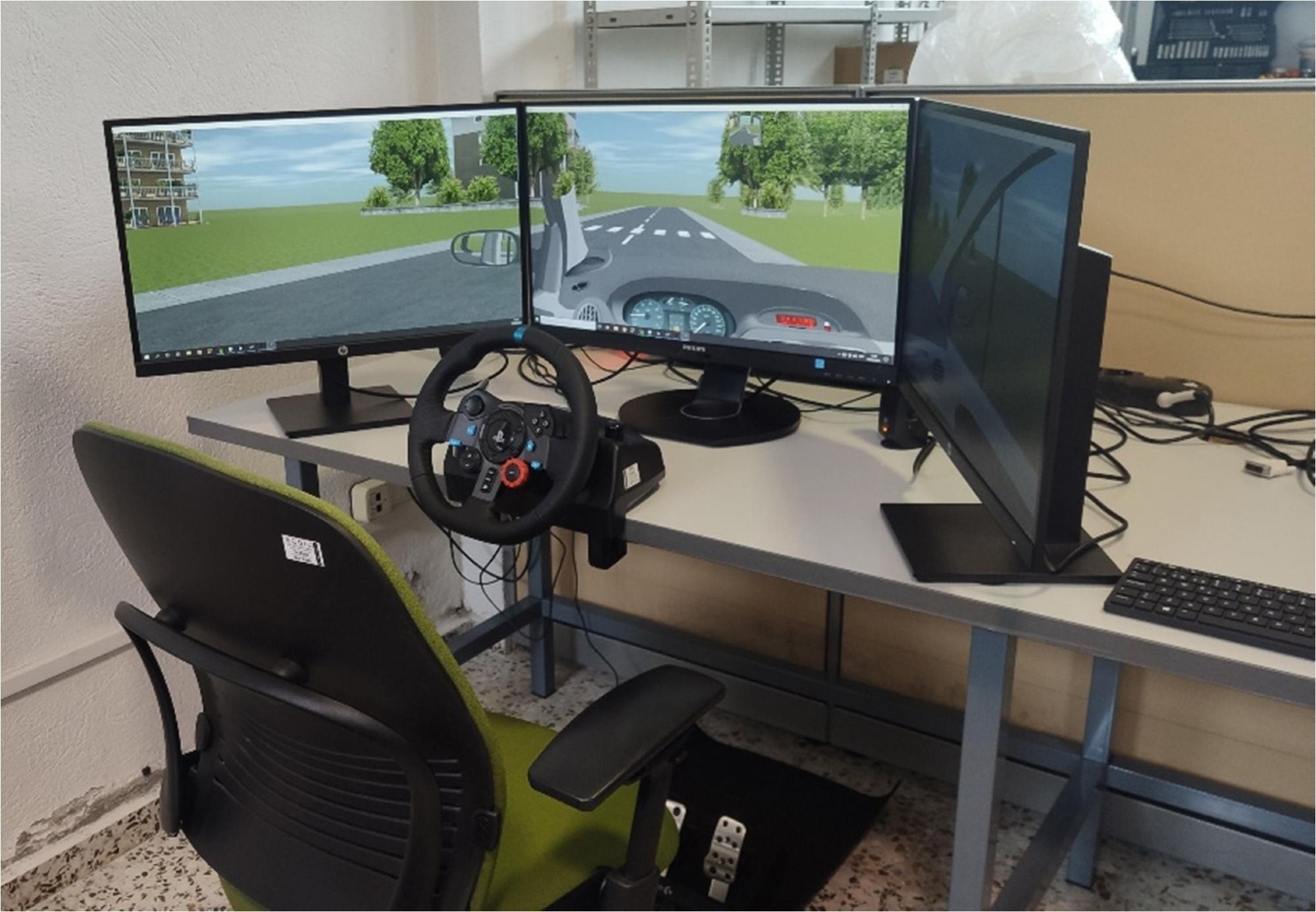 Driving simulator setup used in the experiments, consisting of a steering wheel with pedals, three monitors displaying the virtual driving environment, and a participant’s chair. Study: Cognitive alterations related to driving performance in Parkinson’s disease detected by a driving simulator 