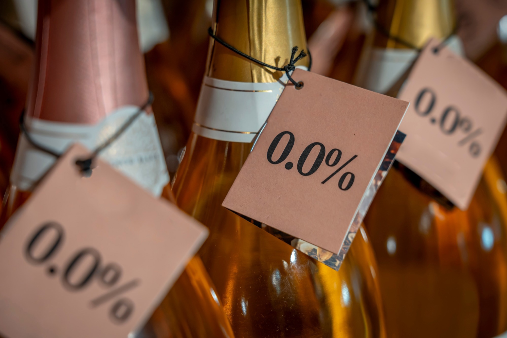 Detail of the neck of three bottles of white wine with a 0.0% alcohol-free label in a store